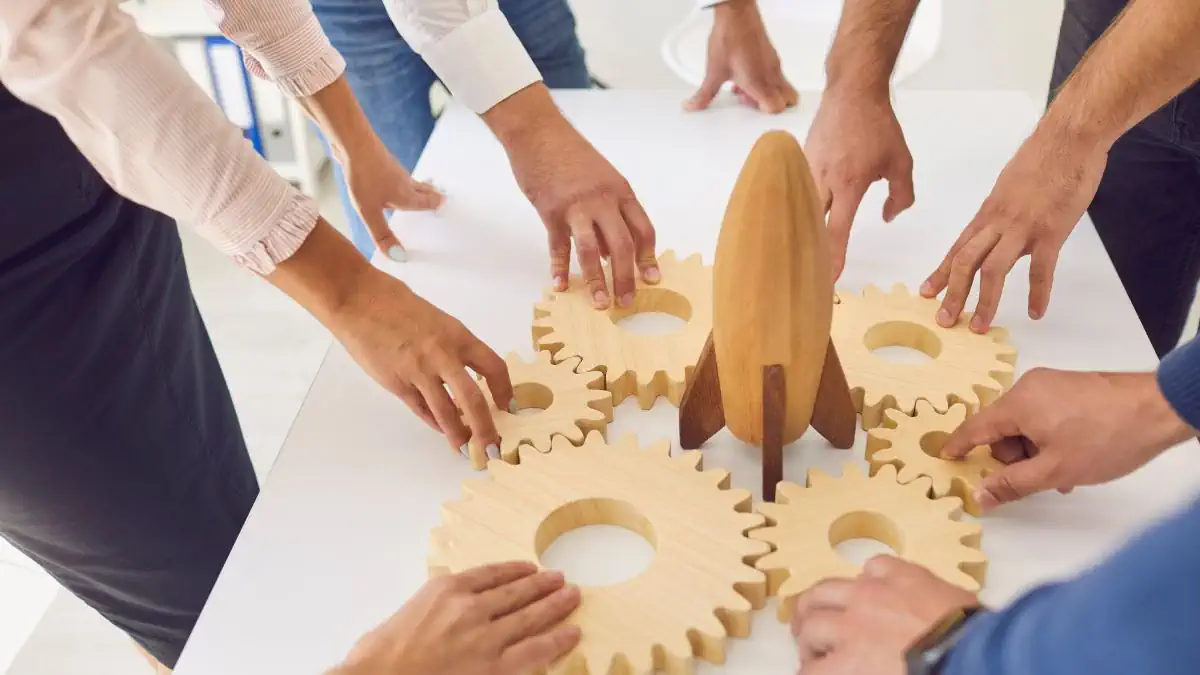 Finding the Right Experts to Help Your Small Business Grow Teamwork concept with wooden gears and rocket symbolizing small business growth
